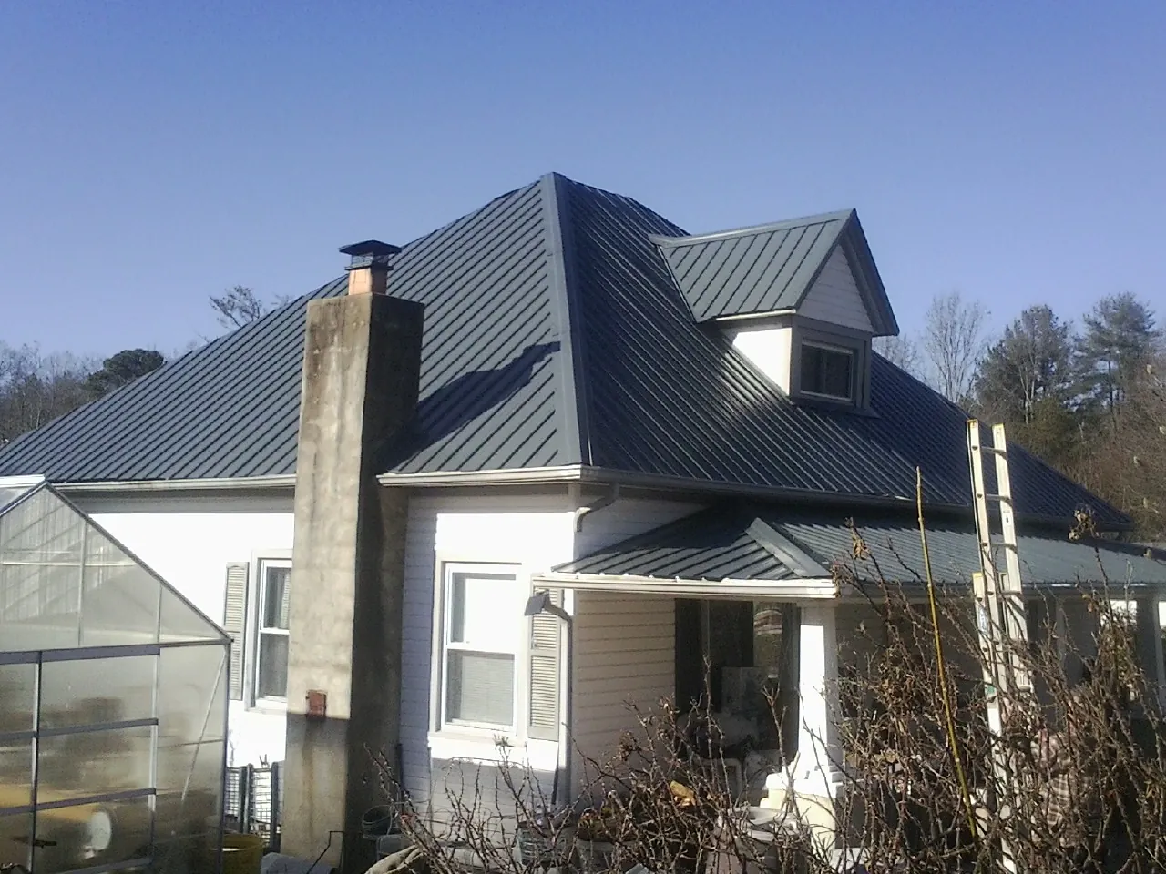 Dark blue standing seam metal roof on a white farmhouse with dormer — Slate & Tile Roof Repair by Roofing Brothers in Hostetter