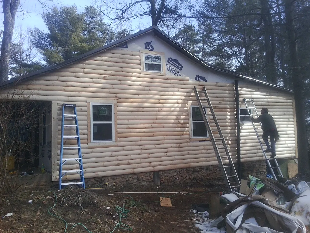 Ladders set against fresh log siding during an exterior remodel in Hostetter