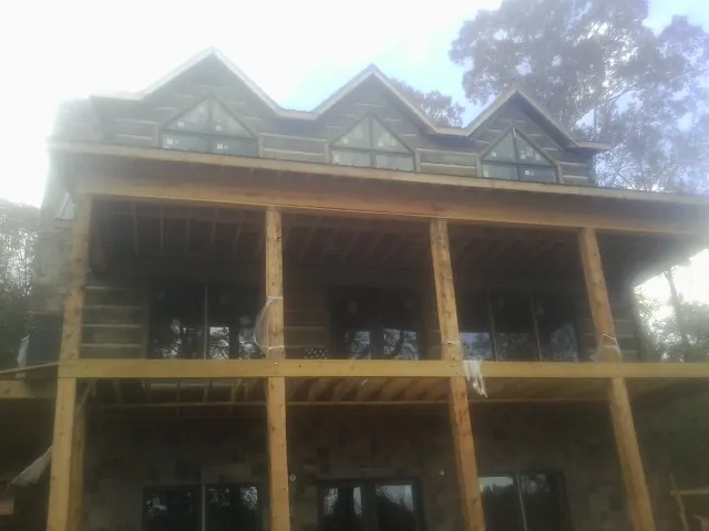 Dormers and porch framing on a large log home under construction — Roof Coating work by our crew in Hostetter