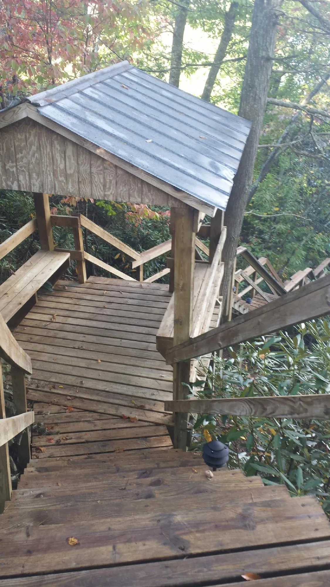 Metal roofed shelter over wooden steps on a wooded walkway — Skylight Repair & Installation work by our crew in Hostetter