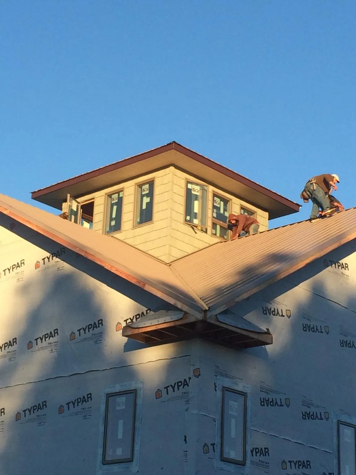 Roofers working around a rooftop cupola on a new metal roof at sunset — Roof Waterproofing in Hostetter by Roofing Brothers